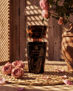 Black Olfazeta by Chogan Millésime N°105 bottle on a wicker placemat, pink roses and a terracotta jar