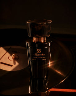 Melns flakons Olfazeta by Chogan Millésime N°88 uz vinila atskaņotāja, dzintara gaisma uz plates